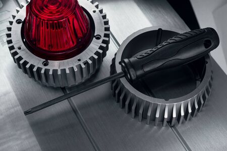 Professional reinforced black matt screw driver placed on a gearwheel. View from the top.の写真素材