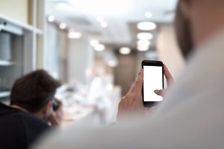 Businessman holding mobile phone in his hand trying to make a picture. Isolated cellphone screen.