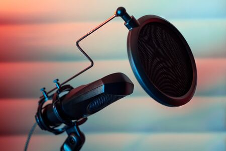 Condenser microphone placed on a tripod with acustic panels in the background in a music studio, ready for recording.の写真素材
