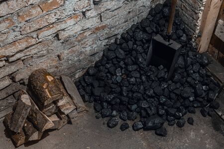 Coal, wood and shovel on the floor at the basement prepared for heating the house with.の写真素材