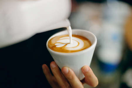 Professional barista pouring latte foame over coffee, espresso and creating a perfect cappuccinoの写真素材