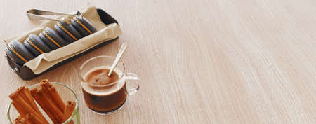 Top view of cup of coffee, coffee macarons, cinnamon stick on wooden table. 3d renderingの写真素材