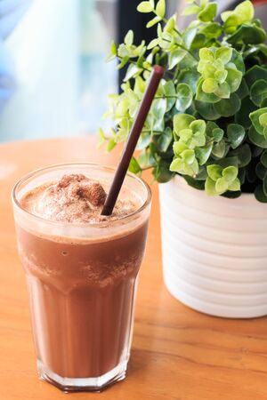Cocoa milkshake on wood table with artificial plantの写真素材