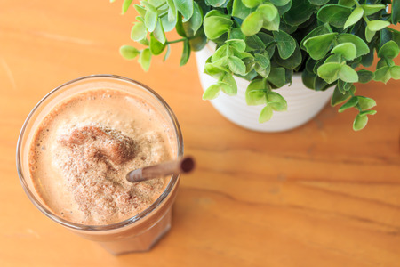 Cocoa milkshake on wood table with artificial plant  birdの写真素材