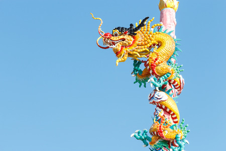 The old statue of gold dragon bind pillar and blue skyの写真素材