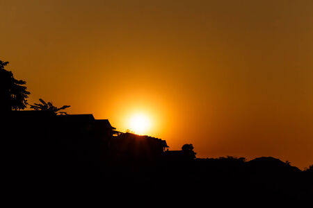 sunset above roof of house in rural scene  silhouette  at Chiang Khan ,Thailandの写真素材