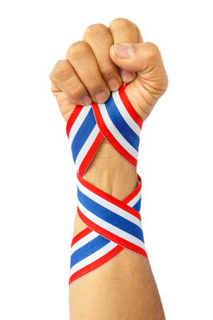 thai man fist and bind thai flag pattern ribbon on forearm on whiteの写真素材