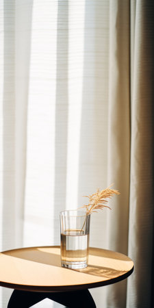 a glass sits on a velvet table next to a window, showcasing a minimalistic japanese style. the black and beige color scheme creates a whimsical ambiance. this minimalist still life captures a sparse and simple yet subtly folk-inspired aesthetic. the photograph, taken by an interior design photographer using a canon eos r5, exhibits a lot of detail in the objects. with a touch of filmの素材