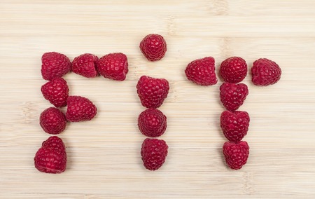 High angle view of fit text made of raspberries on wooden tableの写真素材
