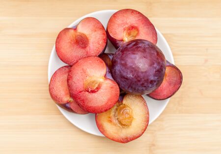 Directly above shot of halved and whole plums in bowl on tableの写真素材