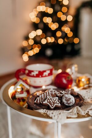 Gingerbread Christmas cookies on silver plate, Christmas gifts and decor close up. Xmas holiday table setting, decorated with cookies, honey, cup, apple and lights.の写真素材