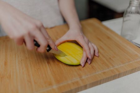 Close up of Woman Holding and Cutting Mango Fruitの写真素材