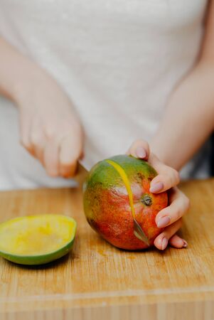 Close up of Woman Holding and Cutting Mango Fruitの写真素材