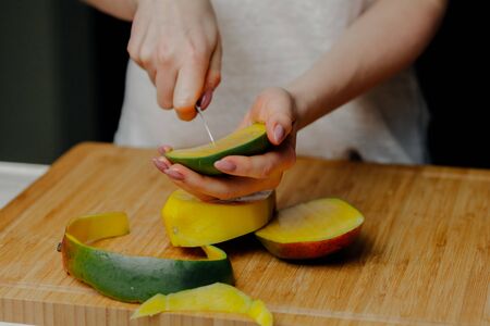 Close up of Woman Holding and Cutting Mango Fruitの写真素材