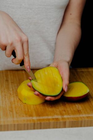 Close up of Woman Holding and Cutting Mango Fruitの写真素材
