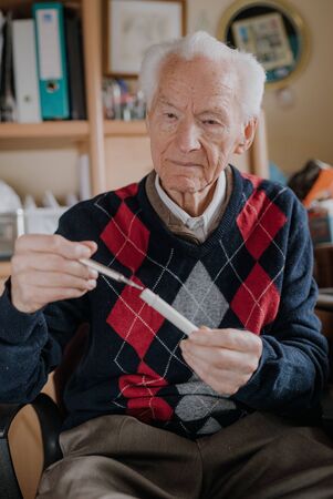 Senior Elderly Man Holding thermometer in Hands.の写真素材