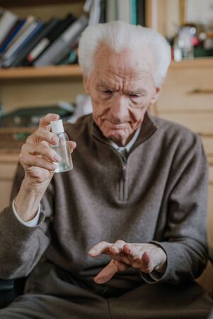 Senior disinfects hands with antibacterial gel