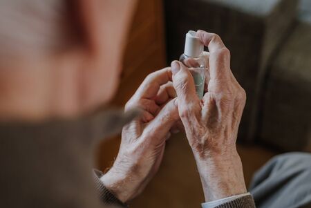 Senior disinfects hands with antibacterial gelの写真素材