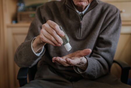 Senior disinfects hands with antibacterial gelの写真素材