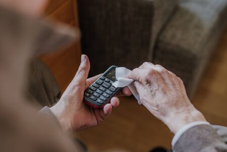 Old Man Cleaning phone to prevent Covid-19 infectionの写真素材