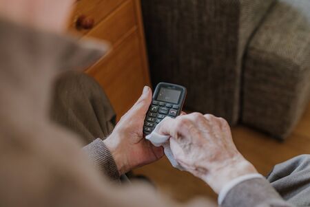 Old Man Cleaning phone to prevent Covid-19 infectionの写真素材