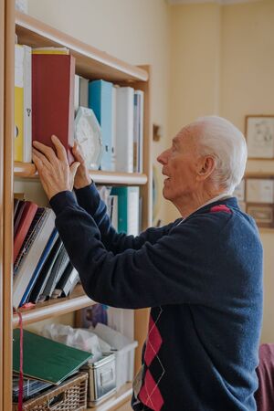 Elderly man reading book at homeの写真素材
