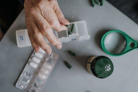 Senior arranges medicines for each day of weekの写真素材
