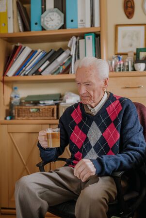 Old man drinking coffee at homeの写真素材