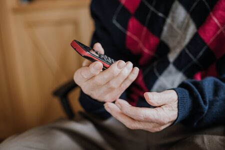 Elderly man talking on phone sitting at homeの写真素材