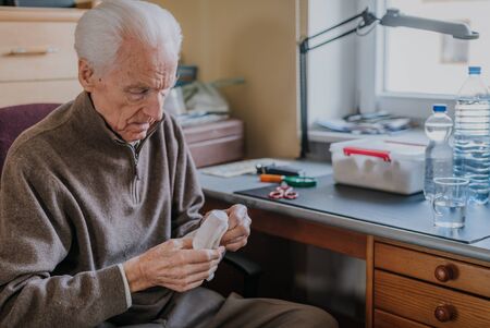 Senior preparing dressing, cuts gauze