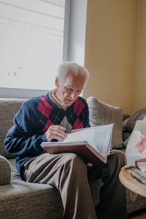 Elderly man reading book at homeの写真素材