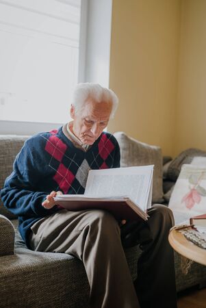 Elderly man reading book at homeの写真素材