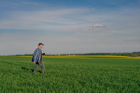 Modern Farmer Researcher Using Digital Tablet at Agricultural Field. Farmer Working on Tablet Computer Against beautiful Rural View.の写真素材