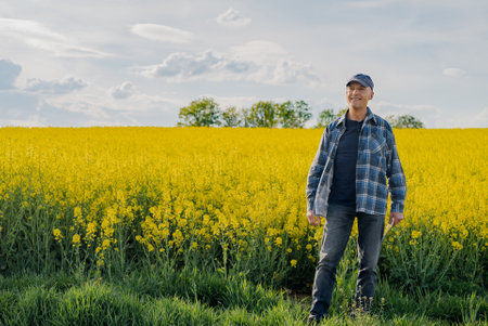 Portrait of Successful Farmer Examining Crops at Agriculture Field. Farmer Looking at Crops Oilseed Fieldの写真素材