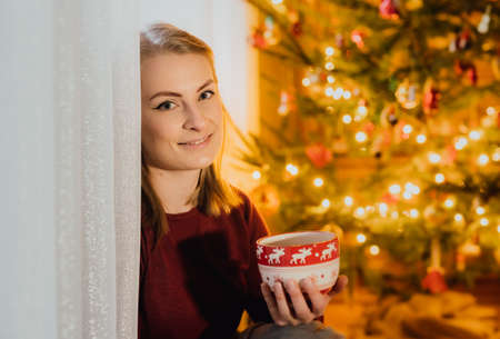 Woman Siting by the Christmas Tree at Christmasの写真素材