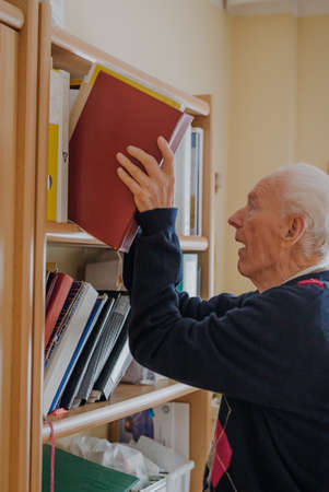 Elderly man reading book at homeの写真素材