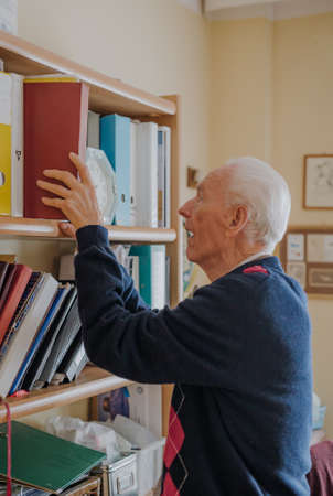 Elderly man reading book at homeの写真素材