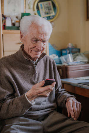 Elderly man talking on phone sitting at homeの写真素材