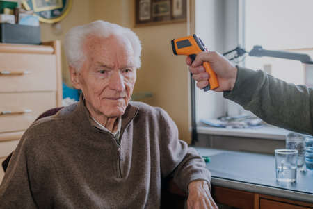 Old man measured temperature with thermometerの写真素材