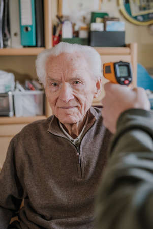 Old man measured temperature with thermometerの写真素材