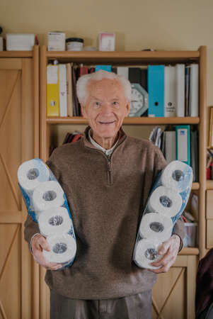 Old man holding two packs of toilet paperの写真素材