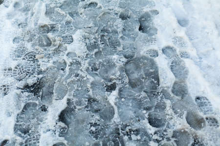slippery sidewalk in winter covered with slush full of footprintsの写真素材