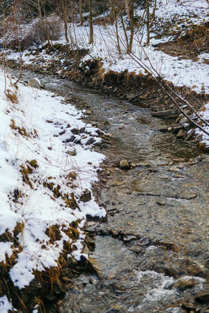 Mountain stream against forest in winterの写真素材