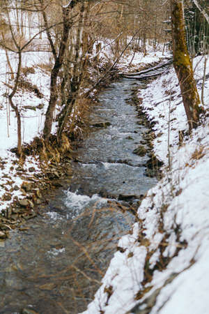 Mountain stream against forest in winterの写真素材