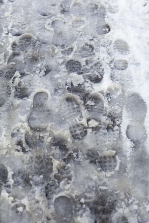 slippery sidewalk in winter covered with slush full of footprintsの写真素材