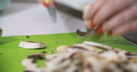 Housewife slicing mushrooms in the kitchen for cookingの写真素材