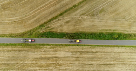 Aerial view of tractor passing road. Agricultural tractor workin on field.の写真素材