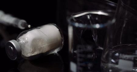 Laboratory Equipement: Syringe and Medicine, Test Tubes and Flasks Rotating on Black Background.