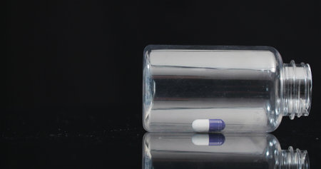 Single Medical Pill in Small Bottle Rotating on Black Background.の写真素材