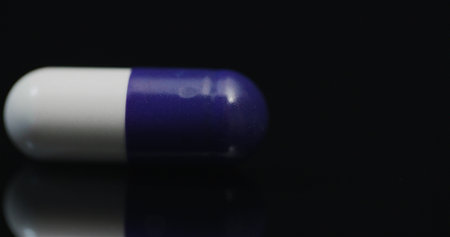 Single Medical Pill Rotating on Black Background.の写真素材